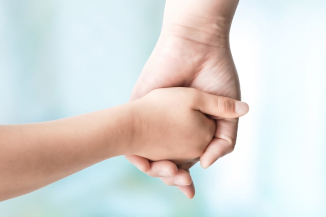 手を繋ぐ子どもと親の手